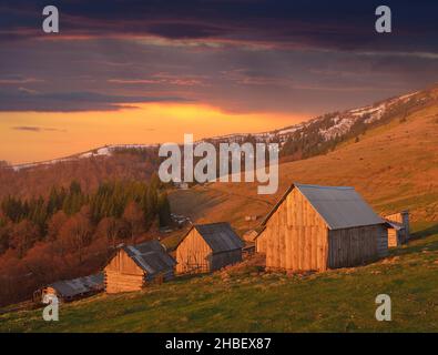 Spring landscape with wooden village of shepherds in the mountains. Light of the setting sun Stock Photo