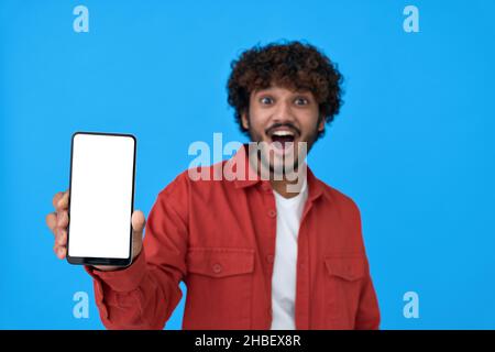Excited young indian man holding cellphone showing big white mockup screen. Stock Photo