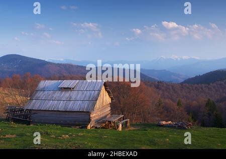 Spring landscape. Old wooden house in mountains. Sunny evening. Village of shepherds. Carpathians, Ukraine, Europe Stock Photo