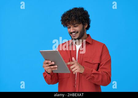 Happy indian guy using digital tablet isolated on blue background. Stock Photo