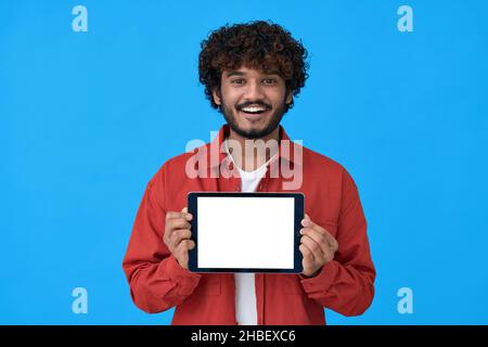 Happy young indian man showing big mockup tablet screen on blue background. Stock Photo