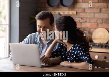 Cheerful emotional young family couple using computer. Stock Photo