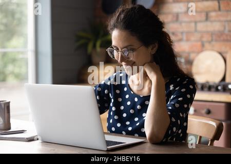 Happy young hispanic woman in eyewear working on computer. Stock Photo