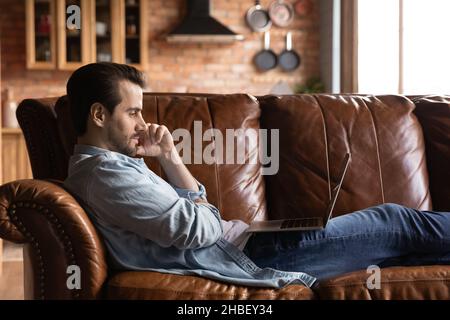 Relaxed young handsome man using computer at home. Stock Photo