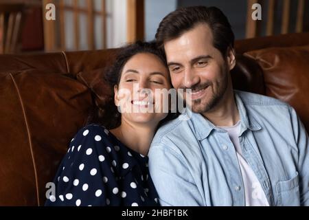 Happy affectionate man and woman resting on cozy sofa. Stock Photo