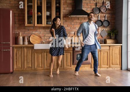 Cheerful young married couple dancing together in kitchen. Stock Photo