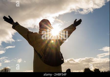 Strong confidence woman open arms under the sunlight in winter park. Happy woman enjoys in sunset. Greeting the sunset. Stock Photo