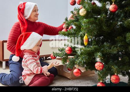 happy family of different generations decorate a Christmas tree in the New Year. Stock Photo