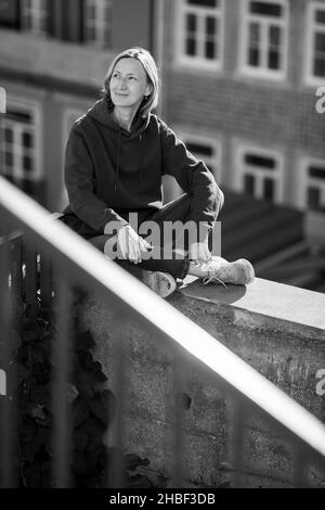 A woman sits in the street of the old town. Black and white photo. Stock Photo