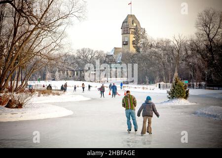 Skating on the duck pond in Assiniboine Park in winter in Winnipeg Manitoba with the Pavilion in the background Stock Photo