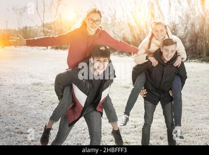 Cheerful teenage boys carrying girlfriends on back Stock Photo