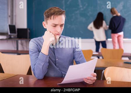 Young thoughtful guy preparing for the exam in classroom Stock Photo