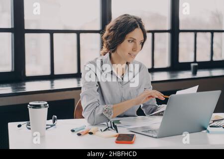 Young successful european businesswoman in formal wear analyzing documents at work Stock Photo