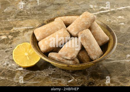 Gingerbread cookies with lemon icing in brown ceramic bowl with fresh lemon half Stock Photo
