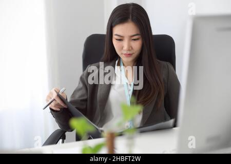A business woman or female accountant looking at the financial report on a binder file at her modern office space. Stock Photo