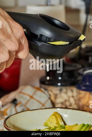 Cook squeezes lemon juice into salad using a special device for preparing salad Stock Photo