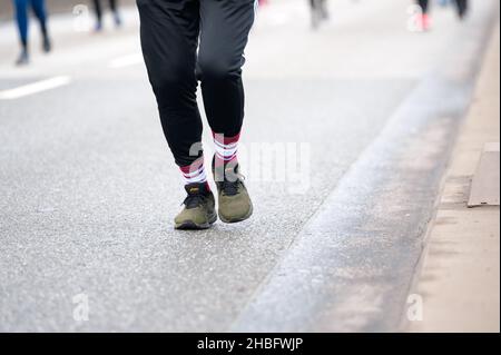 Hamburg, Germany. 19th Dec, 2021. A man runs with sports shoes from the company asics. Around 1700 participants took to the starting line at the eleventh edition of the Köhlbrand Bridge Run. The event was actually supposed to take place on October 3, but was postponed to the fourth Sunday of Advent due to construction work in the harbor. Credit: Jonas Walzberg/dpa/Alamy Live News Stock Photo