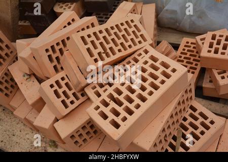 A pile of red perforated bricks, face ceramic bricks on the construction site to finish a house wall. Stock Photo