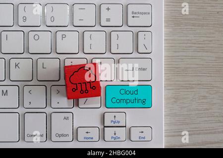 Cloud computing concept. Red wooden cube with cloud icon and keyboard with text Cloud Computing. Stock Photo