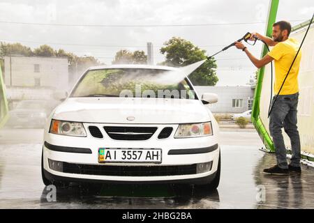 Chernigov, Ukraine - July 24, 2021: A man washes a car. Saab car at the car wash. White Saab 9-3 at a self-service car wash Stock Photo