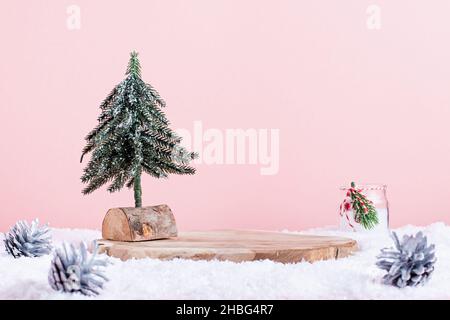 Wooden podium or stand with minimal cristmas tree and candle in snow on pastel pink background. Empty wooden stand to showcase product with Christmas Stock Photo