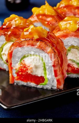 Closeup of sushi roll with cream cheese, tobiko, avocado, seared salmon, mango Stock Photo