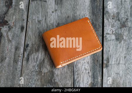 Tan brown leather bifold wallet on wood background DIY craftmanship working Stock Photo