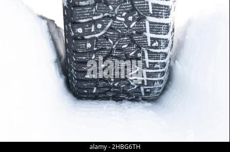 Car tire in the snow close up. Car tracks on the snow. Traces of the car in the snow. Winter tires. Tyres covered with snow at winter road. Winter roa Stock Photo