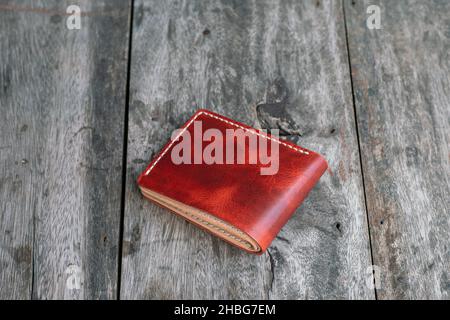 Red genuine cow leather bifold men wallet on wood craftmanship Stock Photo