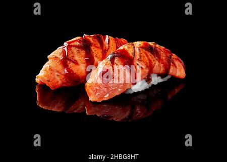 Closeup of nigiri sushi with seared salmon and unagi sauce isolated on black background Stock Photo