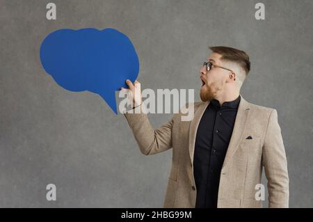 Young adult businessman looking at speech bubble with surprised emotion Stock Photo