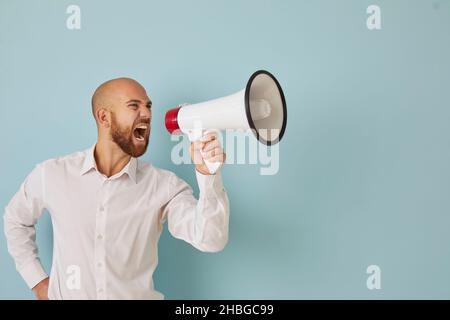 Dissatisfied and angry businessman resolutely makes loud announcement shouting into loudspeaker. Stock Photo