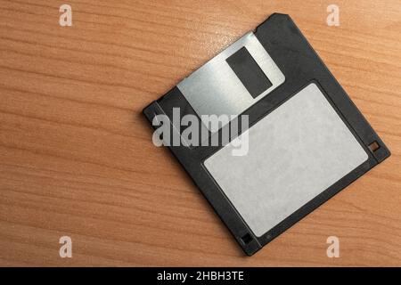 Old 3.5 black floppy disk with blank label on a wooden table Stock Photo