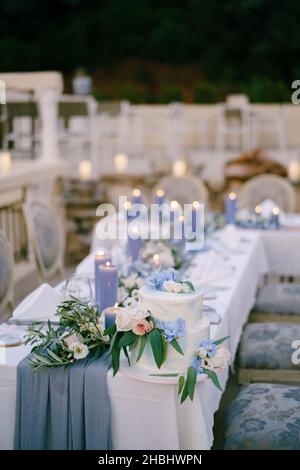 White bunk wedding cake stands on a set table with candles Stock Photo
