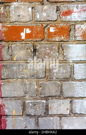 Interesting section of urban brick wall with some bricks pristine and others marred, smudged, or chipped. Useful for background texture Stock Photo