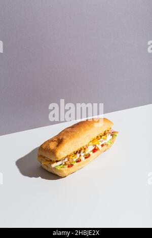 baguette sandwich with chicken salad on grey hard shadow Stock Photo