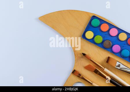 Multi tools artists paint brushes the watercolor box paints and wood palette on white background Stock Photo