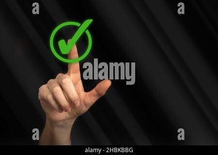 Hand with done check list, concept of do to and planning. Hand touch green mark on a black background photo Stock Photo
