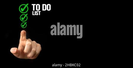 To do list with checklist boxes. Hand marking check list on a black background, banner Stock Photo