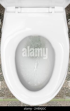 Flushing the water in the toilet in the bathroom Stock Photo