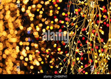 Festive lights on electric garlands. Colorful Christmas illumination, New Year decorations in a shop Stock Photo