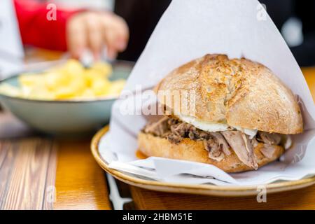 Delicious bun with delicate piglet and egg with chips aside, Portugal Stock Photo