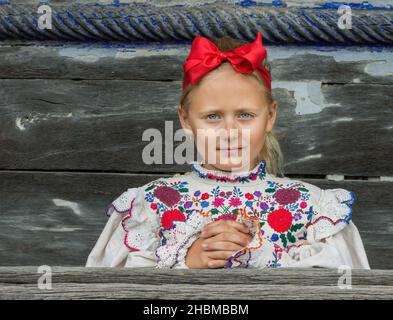 Salaj, Romania-May 15, 2018: Children wearing traditional Romanian costumes in front of a old wooden church in Transylvania region, Romania. Stock Photo