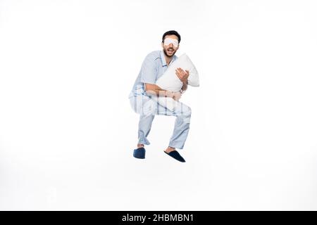 happy man in pajamas and sleeping mask levitating with pillow on white Stock Photo