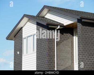 View of detached house with white window frame on gray brick wall and concrete tiles Stock Photo