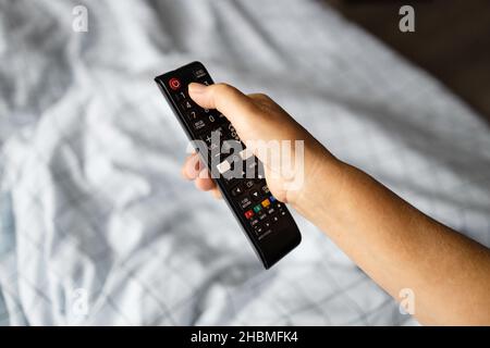 Switching television channels on TV, enjoying sunny morning in bed in a cozy room Stock Photo