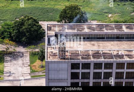 Smoke coming out of the four metal Chimney on the flat roof off a big building in the city. No focus, specifically. Stock Photo