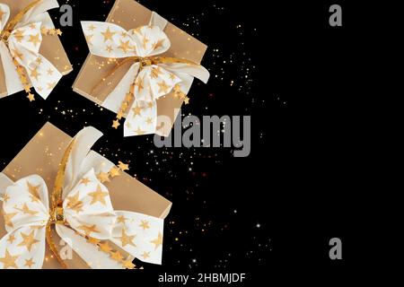 Flying golden gift boxes with twinkling stars against dark background. Stock Photo