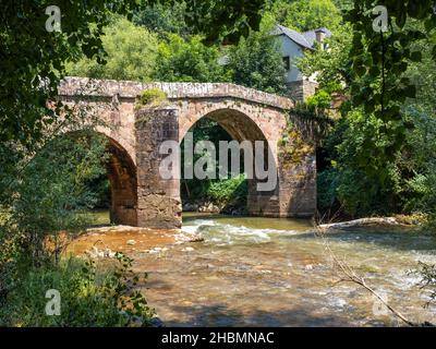 Roman stone bridge of Conques on the Way of St. James,  crossing a tumultuous small river, taken on a sunny summer morning, with no people Stock Photo