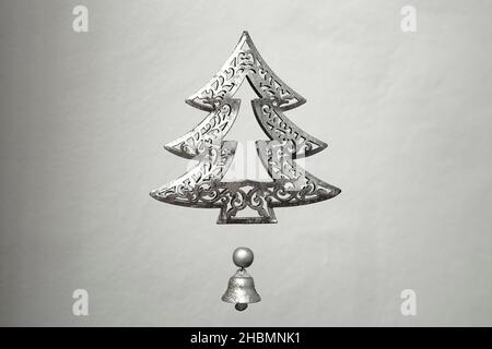 metal christmas tree and little bell, levitating on a grey background Stock Photo